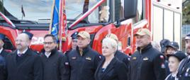 Zdjęcie pamiątkowe uczestników uroczystości na tle nowego samochodu pożarniczego