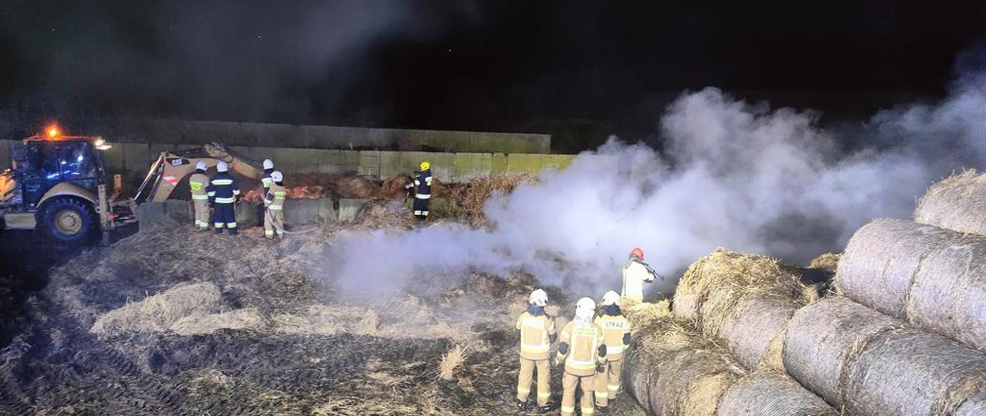 Działania ratownicze przy pożarze balotów słomy.