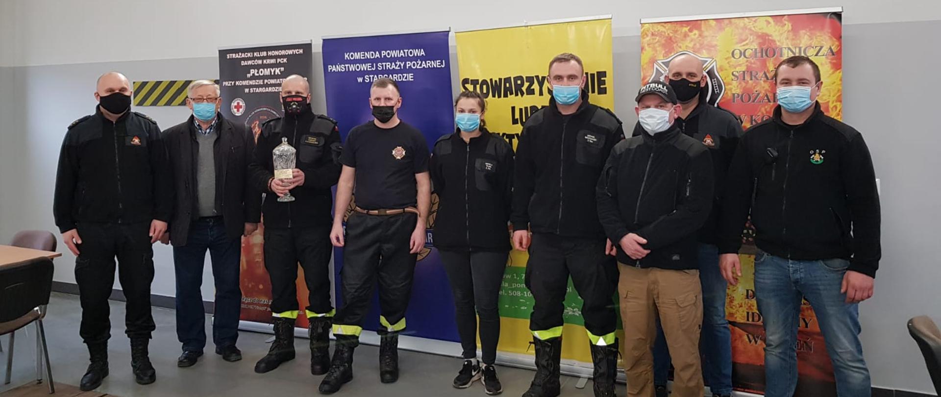 Zdjęcie zbiorowe, strażak trzyma kryształowy puchar
