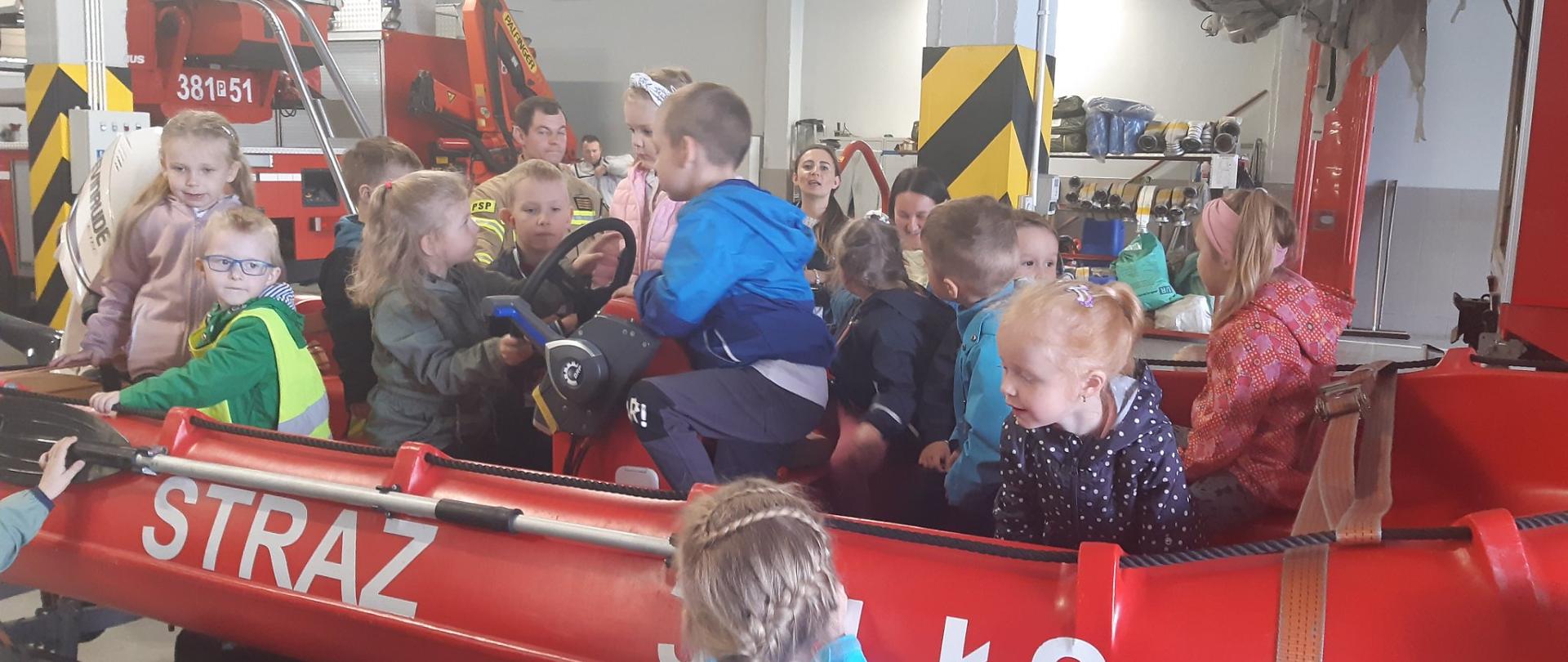 Dzieci siedzą we wnętrzu łodzi motorowej w pomieszczeniu garażowym.