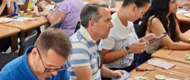 A group of people sitting at tables and sewing as part of the “Qlubija: The Courage to Learn” event.