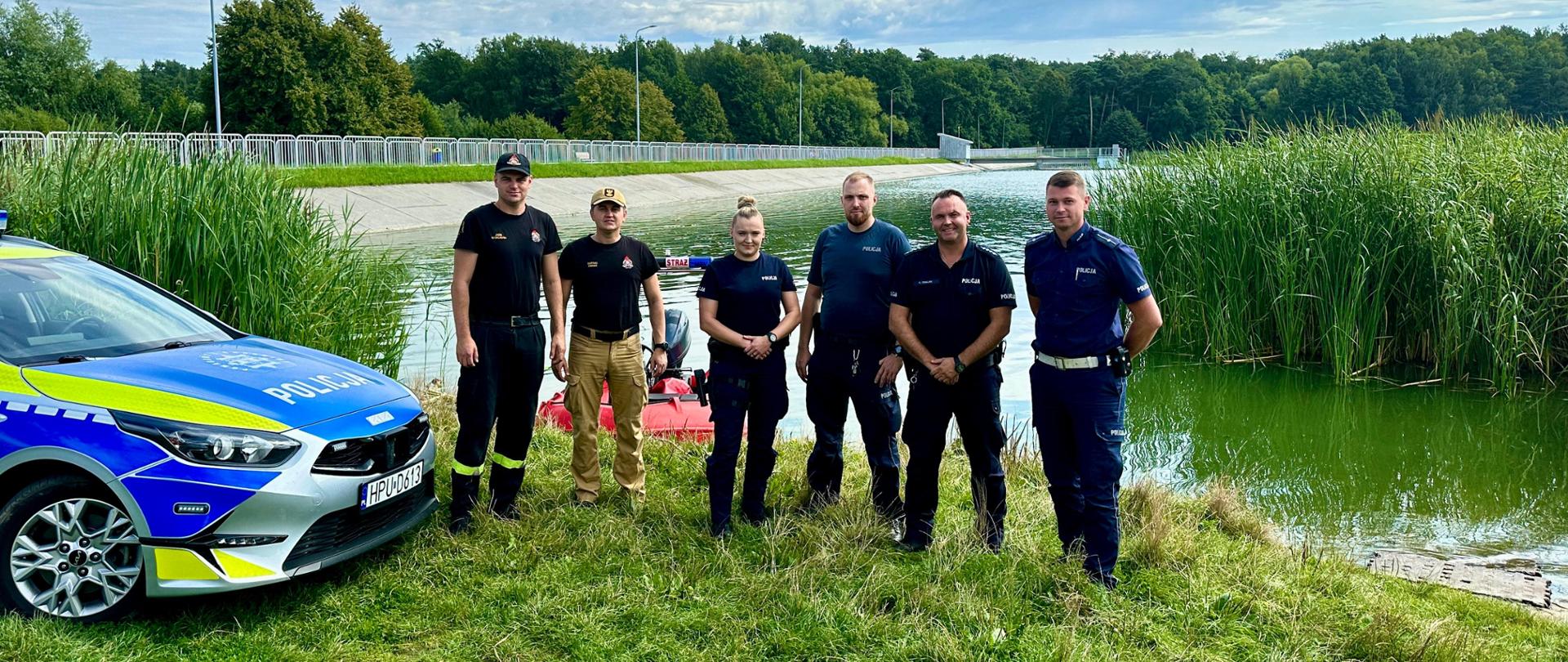 grupa osób na brzegu jeziora pozując do zdjęcia