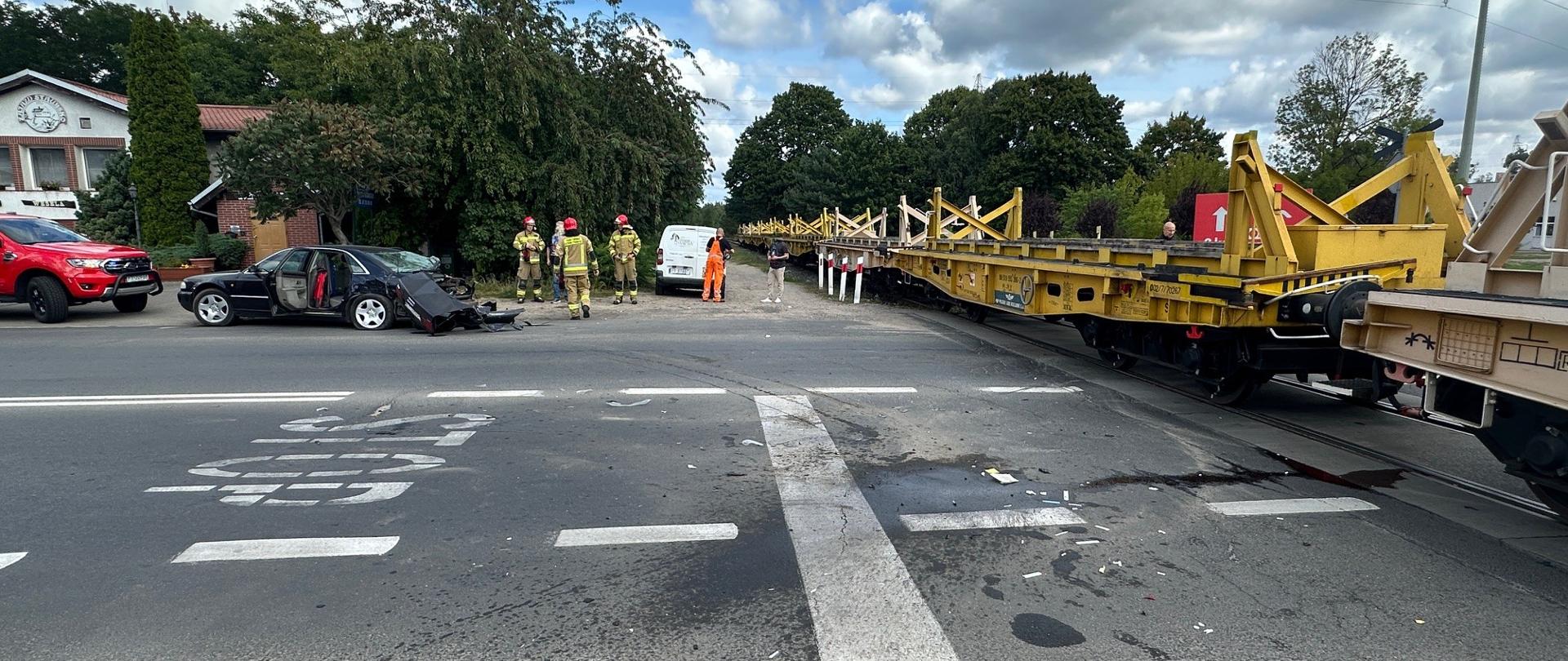 Na zdjęciu widnieją strażacy w trakcie działań ratowniczych podczas zderzenia samochodu osobowego z pociągiem. 