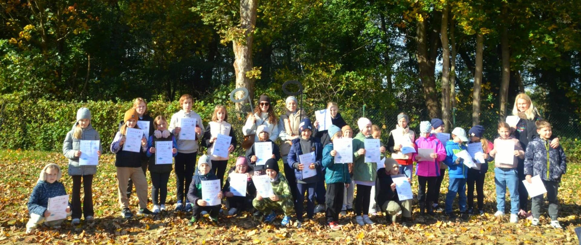 Grupa uczniów klas I i nauczycieli w lesie