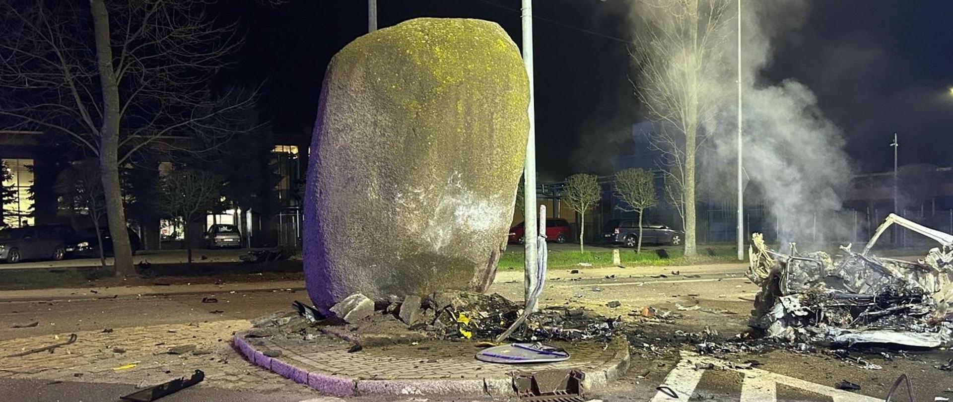 Fotografia przedstawia ujęciu głazu narzutowego w który uderzył pojazd, wrak pojazdu widoczny po prawej stronie