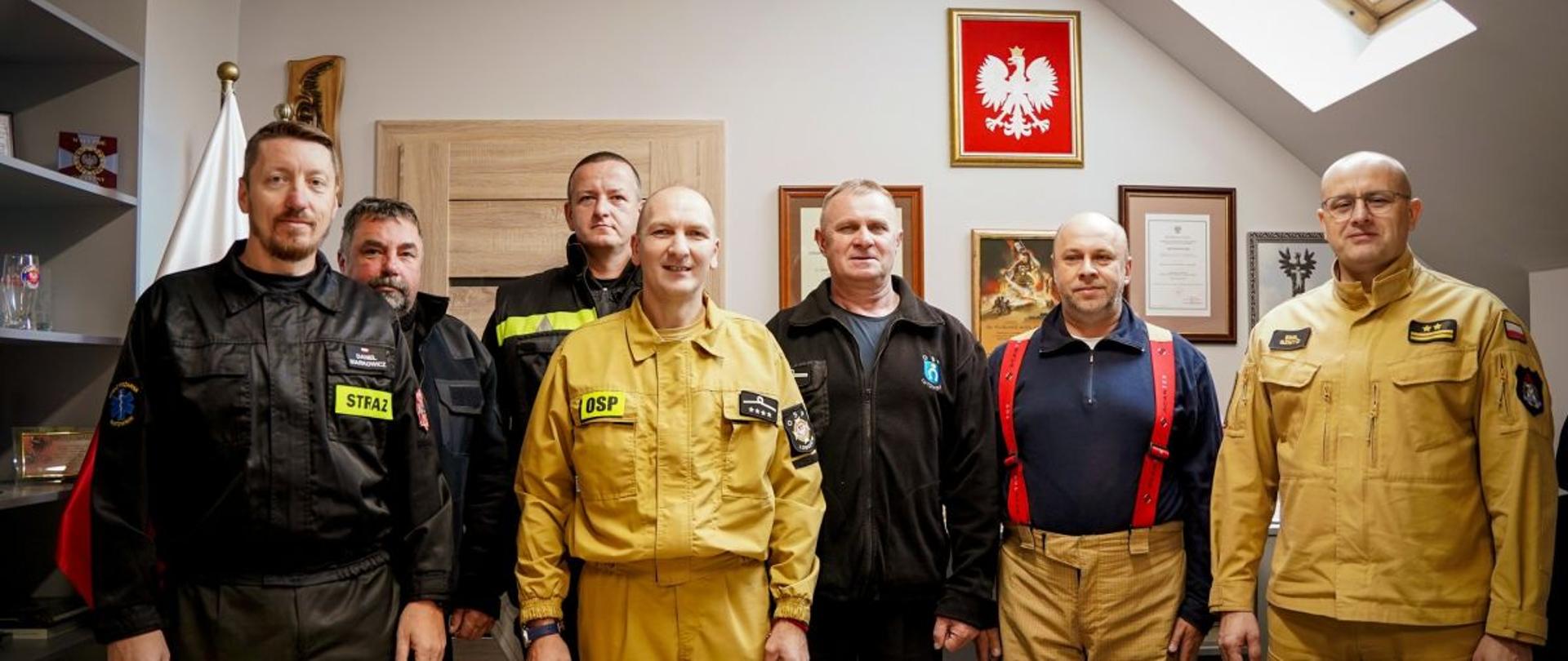 Zdjęcie przedstawia komendanta powiatowego wraz z druhami OSP w biurze. 