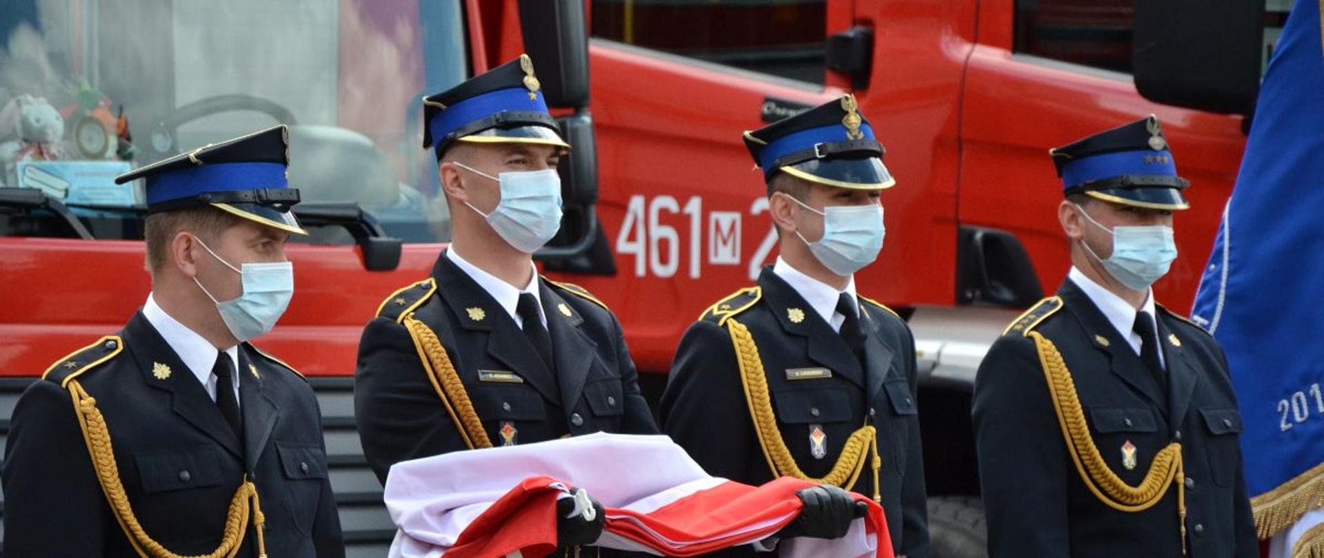 czterech strażaków, w tym jeden trzyma flagę