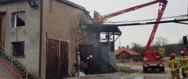 Strażacy gaszący budynek z czerwonego podnośnika koszowego.