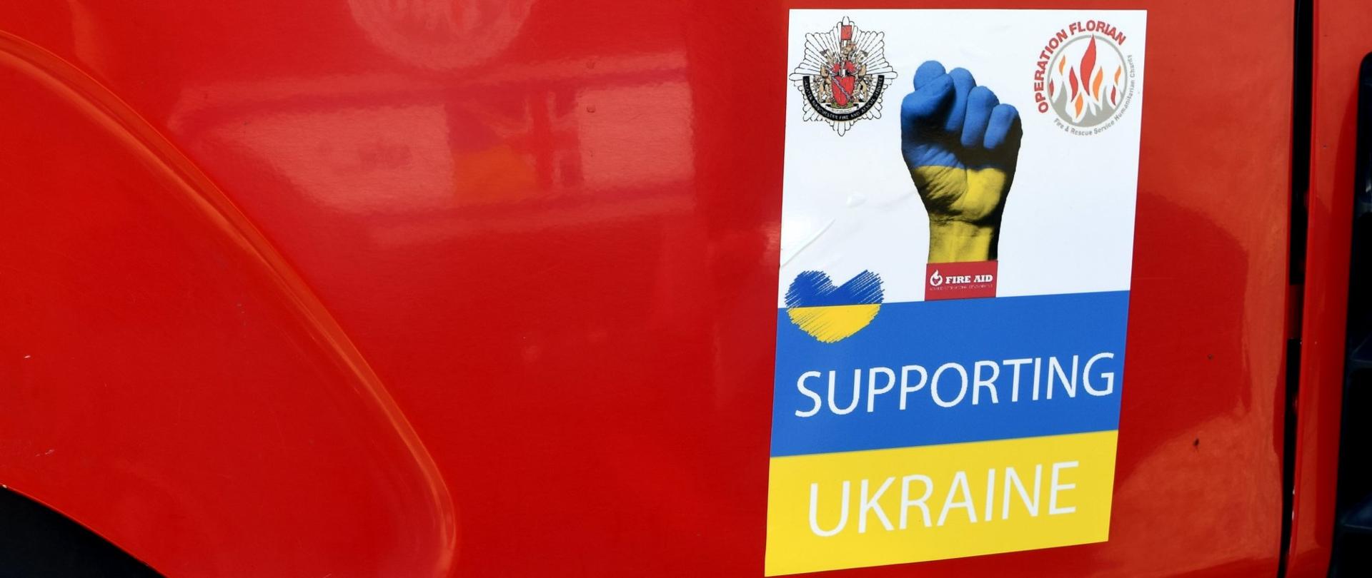 Naklejka na samochodzie pożarniczym. Na naklejce napisane jest supporting Ukraine.