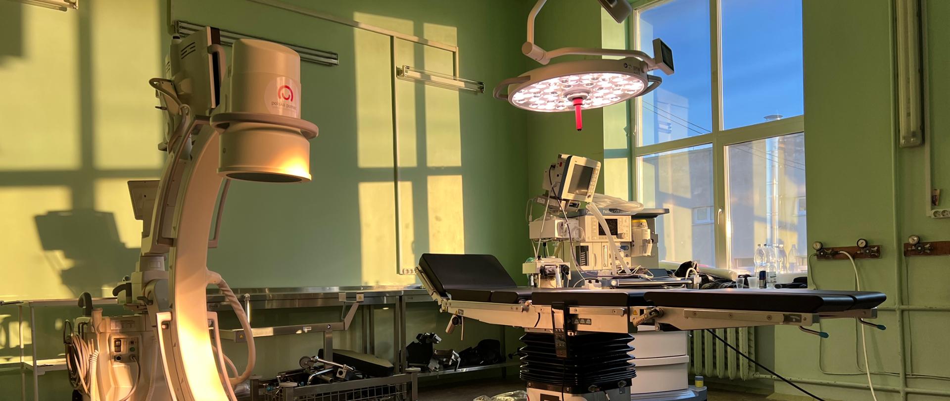 Sala operacyjna z widocznym stołem operacyjnym oznakowanym logo Polska pomoc