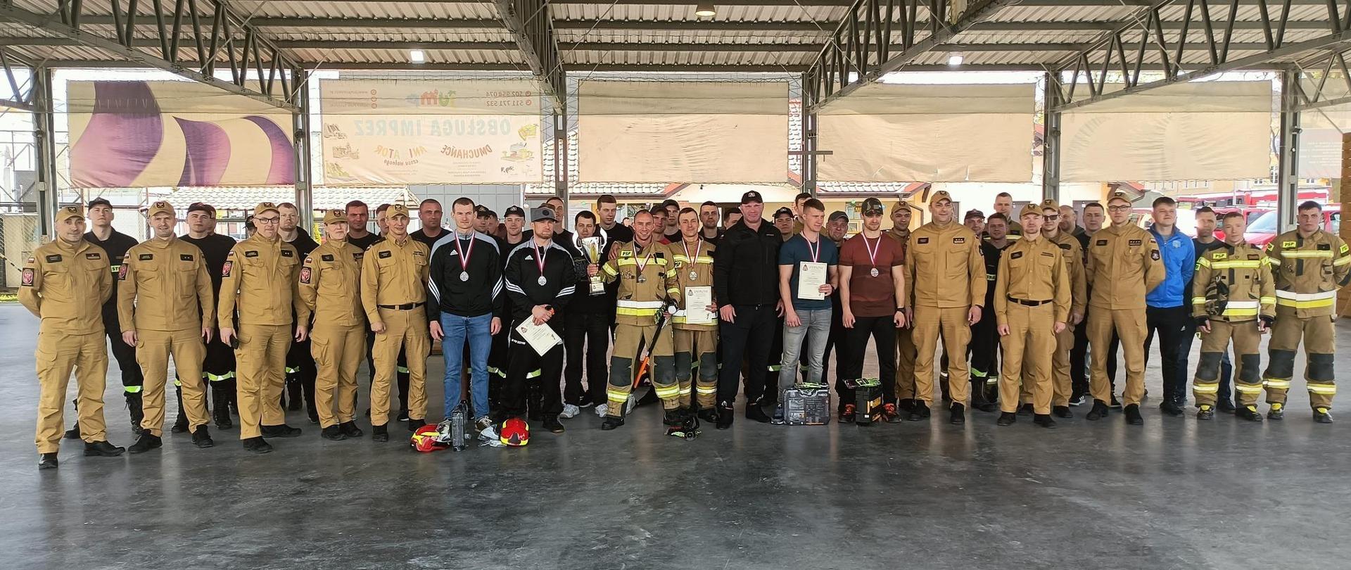 Na zdjęciu duża grupa strażaków w mundurach, uczestnicy i organizatorzy zawodów.