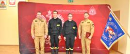 Nowi strażacy w obecności komendantów na ściance obok sztandar
