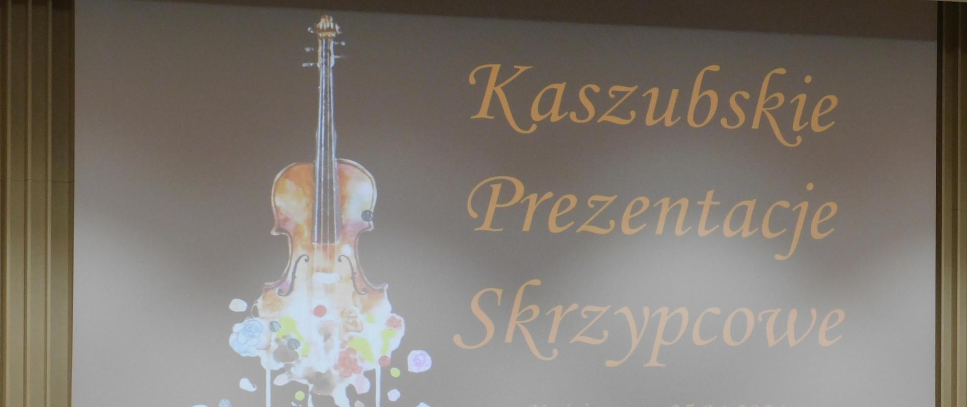 Na zdjęciu na pierwszym planie czarny fortepian, a za nim na białym ekranie wyświetlony na czarnym tle po prawej stronie pomarańczowy napis "Kaszubskie Prezentacje Skrzypcowe Kościerzyna 25.04.2024". Po lewej stronie grafik skrzypiec.