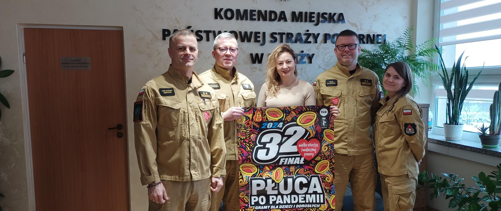Grupa strażaków wraz z szefem sztabu WOŚP pozuje do zdjęcia
