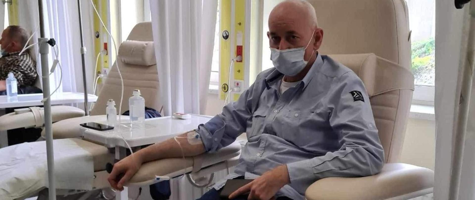 strażak potrzebujący pomocy siedzi na fotelu przyjmując kroplówkę 