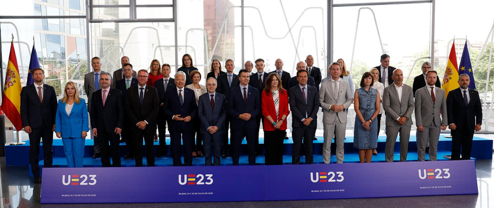 Wiceminister Kamila Król na posiedzeniu nieformalnej Rady ds. Konkurencyjności w Bilbao. Zdjęcie przedstawia wszystkich uczestników posiedzenia. Po prawej i lewej stronie ustawiona jest flaga UE i Hiszpanii. Przed uczestnikami na podłodze, długi, niebieski baner UE 2023 r.