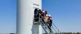 Zdjęcie przedstawia strażaków wchodzących do turbiny wiatrowej