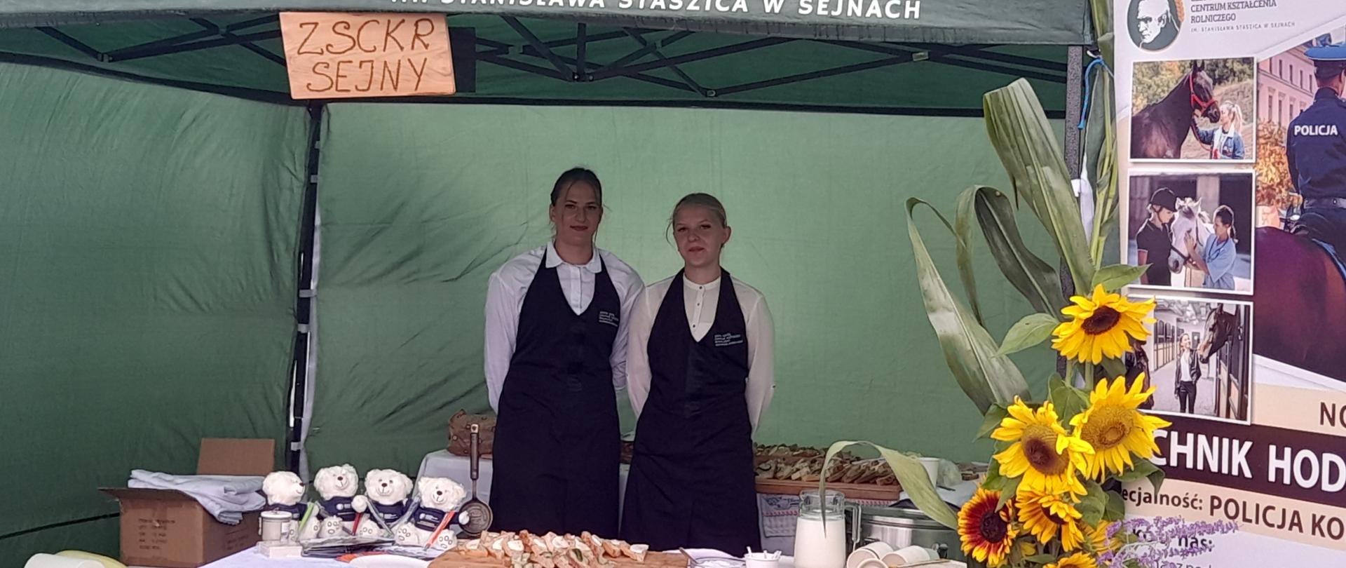 Dwie uczennice obsługujące stoisko promocyjne szkoły