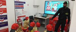 Zdjęcie przedstawia dzieci z Przedszkola Publicznego nr 3 im. Kubusia Puchatka oraz strażaka podczas zajęć w sali edukacyjnej.