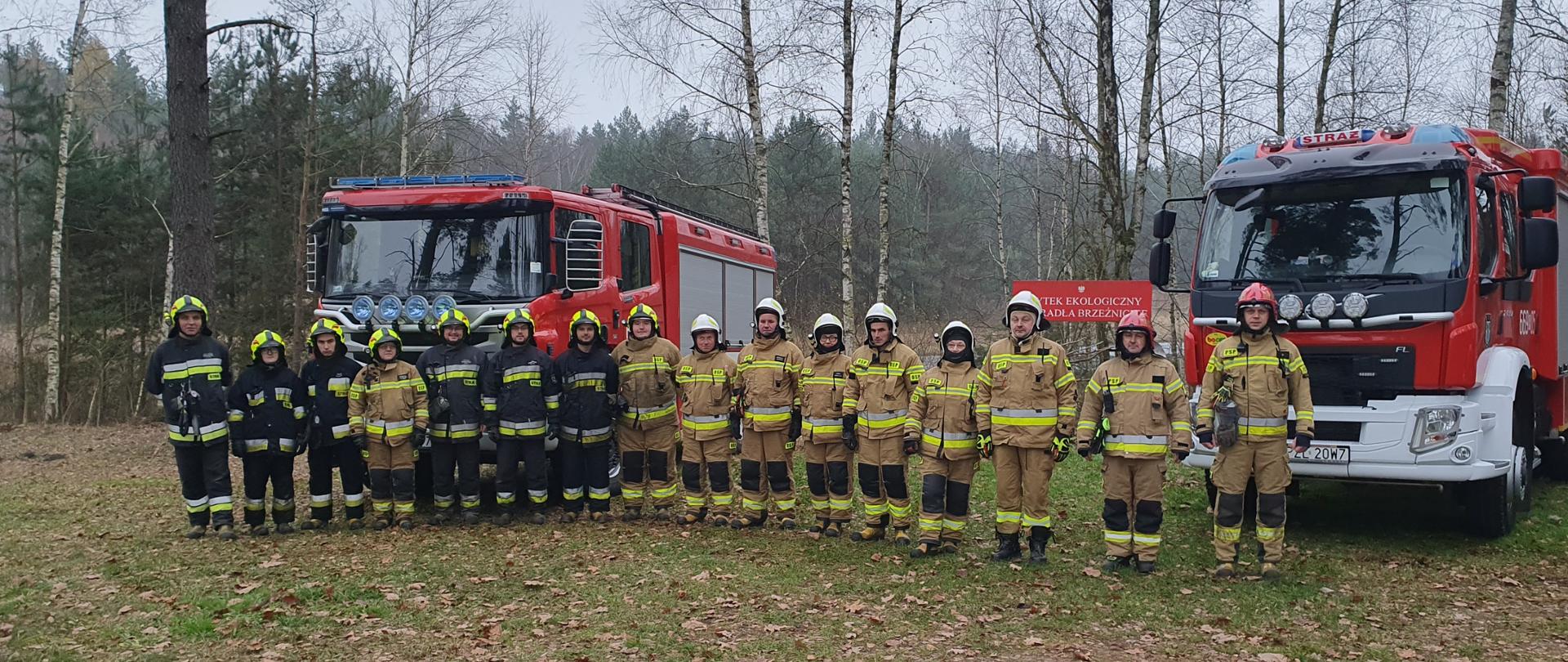 Strażacy przed samochodami strażackimi