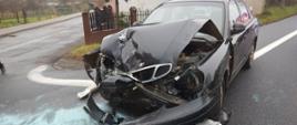 Zdjęcie przedstawia rozbity przód samochodu osobowego marki Daewoo Nubira koloru czarnego