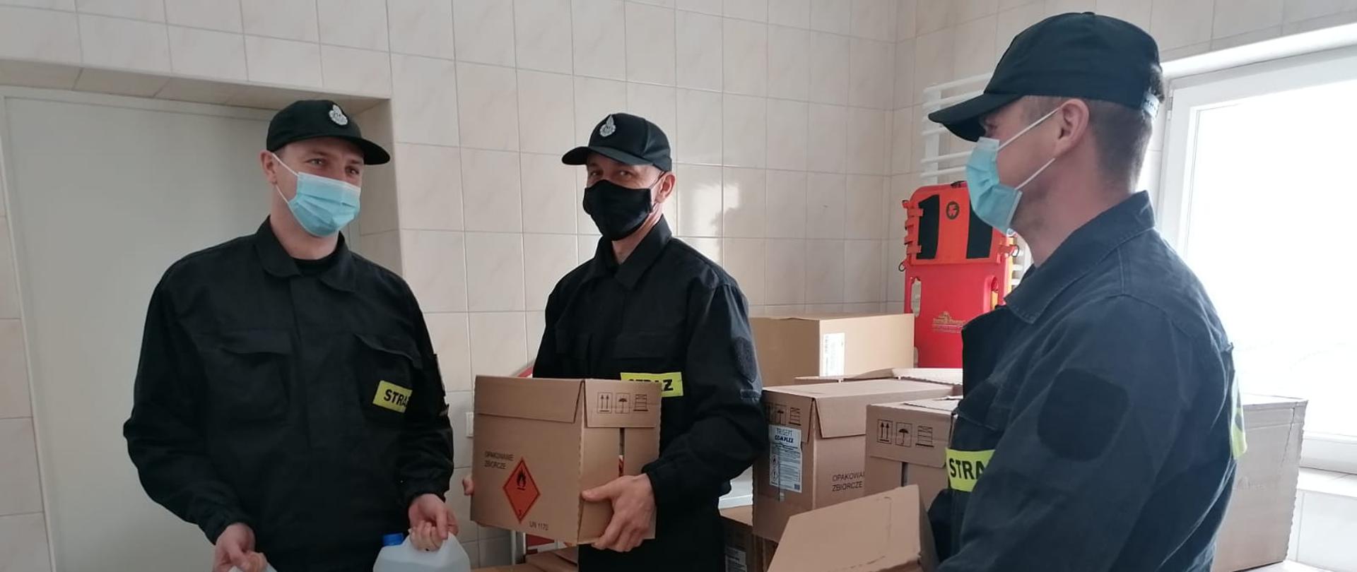 3 strażaków dystrybuujących środki ochrony