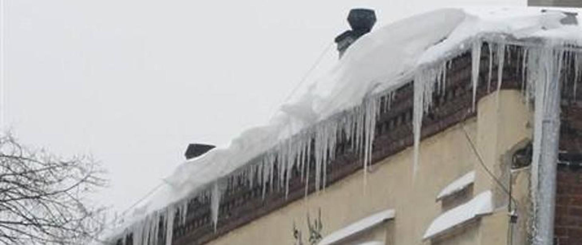Na zdjęciu dach z którego zwisają duże sople lodowe i zalega dużo śniegu