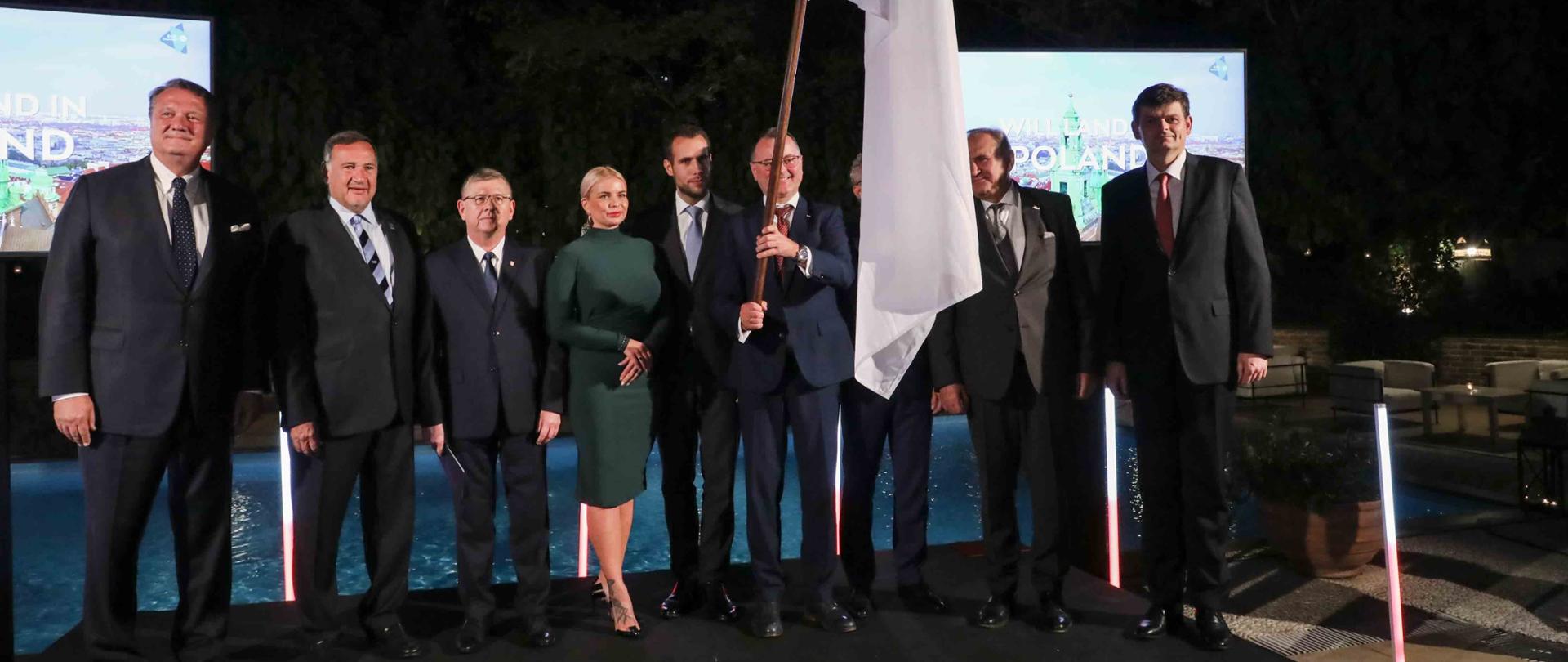 Family photo uczestników 42. Seminarium Stowarzyszenia Europejskich Komitetów Olimpijskich EOC. Jeden mężczyzna trzyma flagę. 