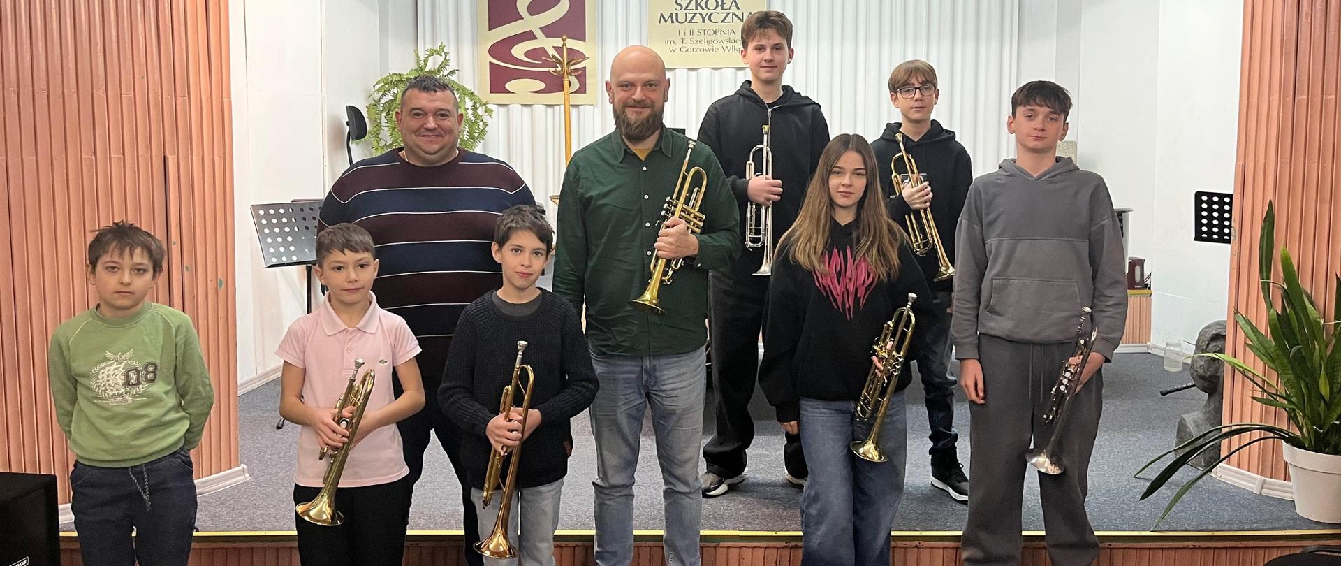 Uczniowie i nauczyciele z trąbkami na scenie