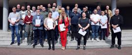 Pamiątkowe zdjęcie grupowe uczestników szkolenia inspektorów ochrony przeciwpożarowej (27 osób) w towarzystwie oficera CS PSP oraz kobiety
