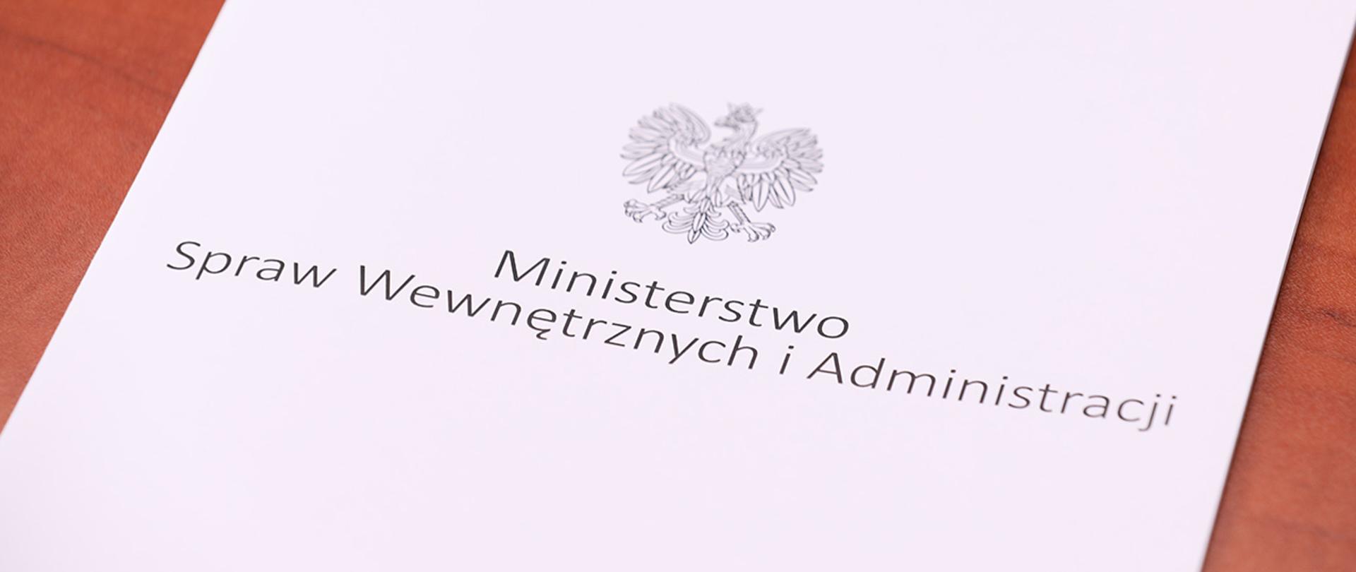 Na zdjęciu widać leżącą teczkę z napisem "Ministerstwo Spraw Wewnętrznych i Administracji" i orłem z godła narodowego.