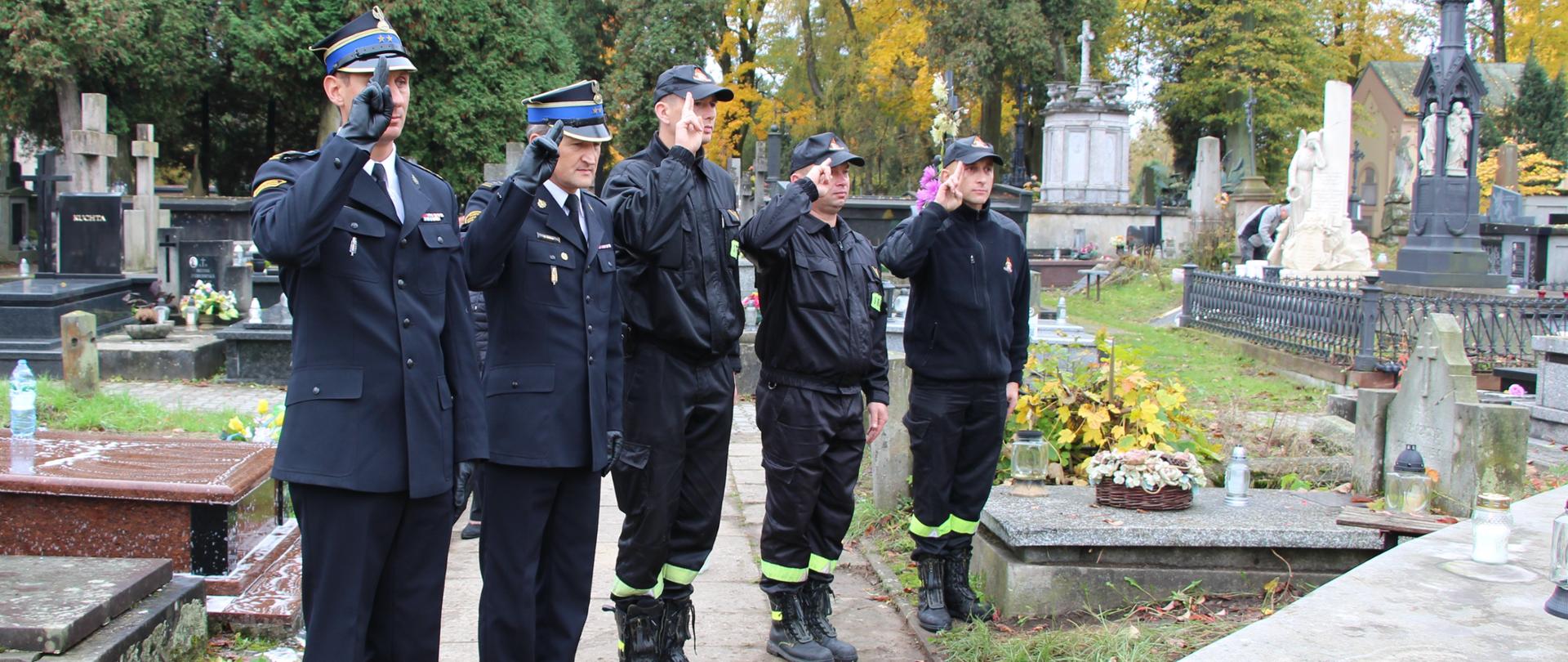 Zdjęcie przedstawia komendantów miejskich Państwowej Straży Pożarnej w Kielcach, którzy wraz z funkcjonariuszami oddają honor przy grobie zasłużonego dla ochrony przeciwpożarowej.