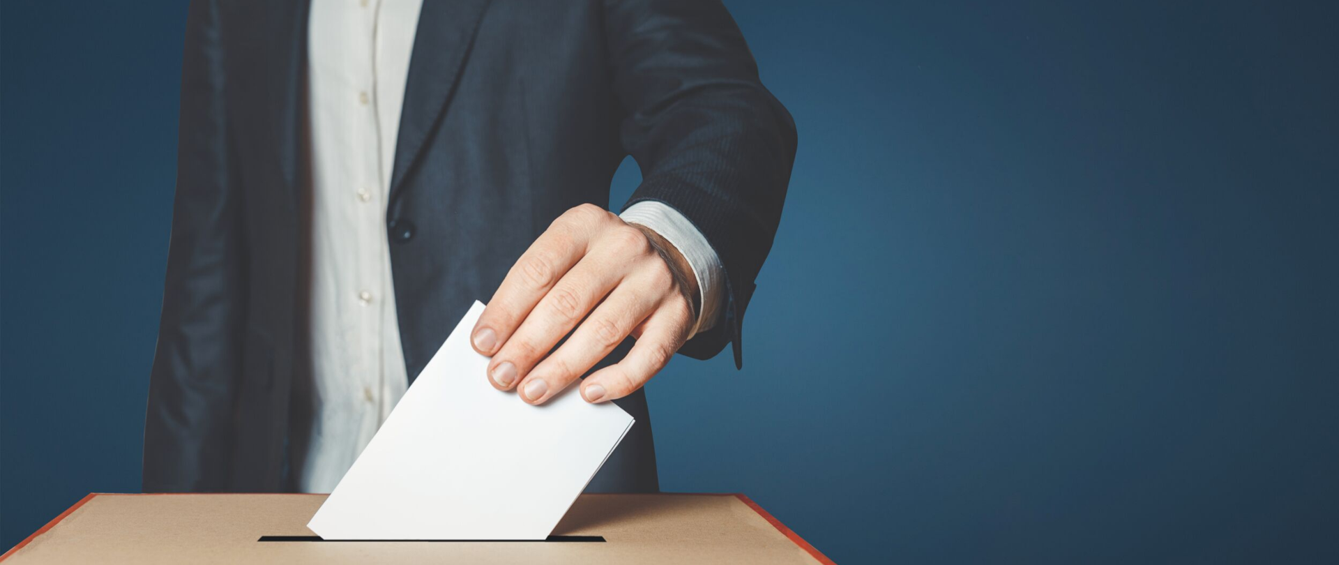 Mężczyzna wrzucający kartę do głosowania do urny wyborczej.