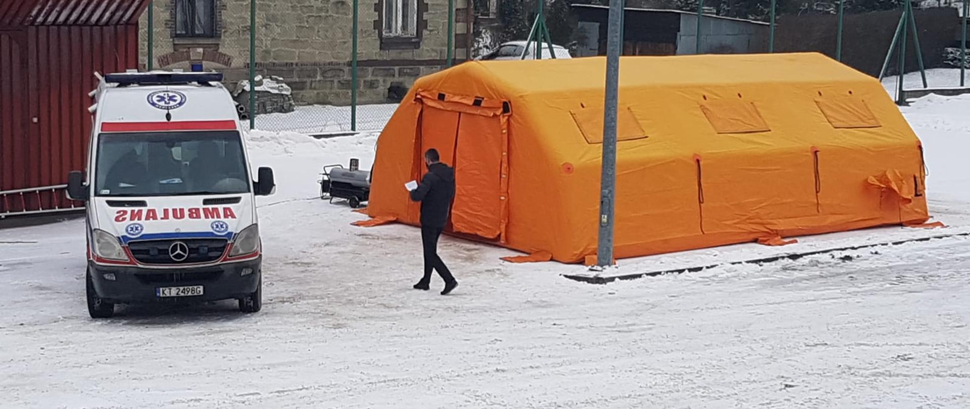 Zdjęcie przedstawia karetkę pogotowia. Obok stoi namiot KP PSP Sucha Beskidzka