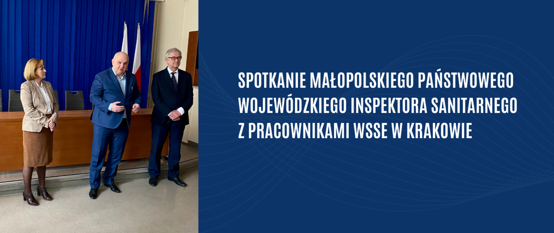 Na zdjęciu po lewej stronie w sali znajduje się kobieta z jasnymi włosami, w beżowej marynarce i brązowej spódnicy. Obok znajdują się dwaj mężczyźni w garniturach. Po prawej stronie znajduje się informacja Spotkanie Małopolskiego Państwowego Wojewódzkiego Inspektora Sanitarnego z pracownikami WSSE w Krakowie