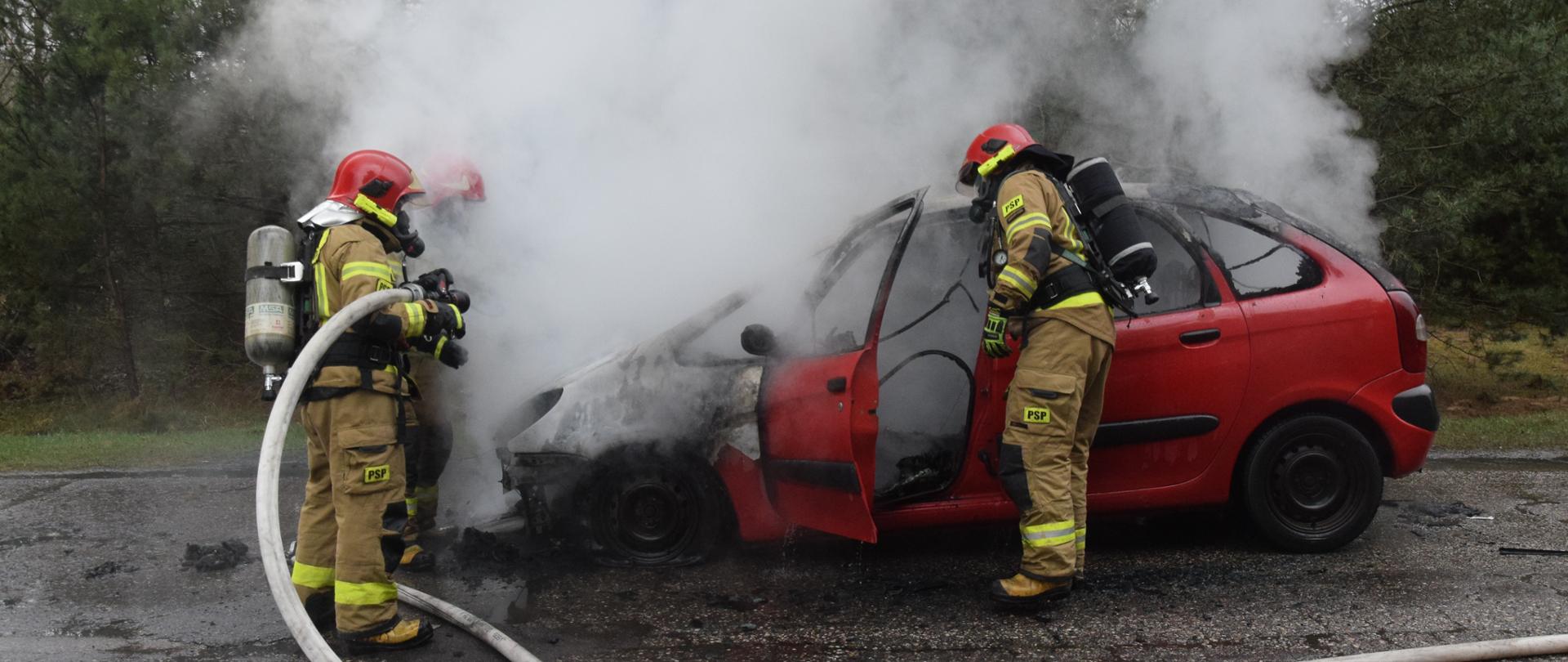 Strażacy gaszą czerwony samochód osobowy
