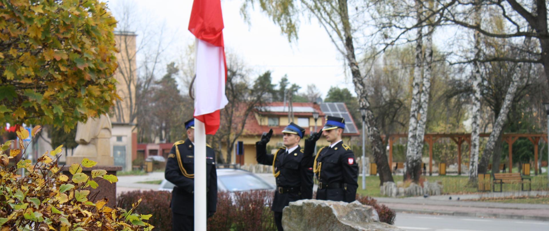 Strażacy oddają honor podczas podnoszenia flagi państwowej na maszt