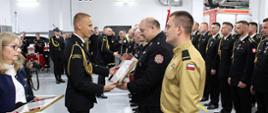 Na zdjęciu widoczny Małopolski Komendant Wojewódzki wręczający Dyplomy z okazji 30-lecia utworzenia Krajowego Systemu Ratowniczo-Gaśniczego druhom z jednostek Ochotniczych Straży Pożarnych z powiatu gorlickiego podczas apelu z okazji Dnia Strażaka 2025 w KP PSP w Gorlicach