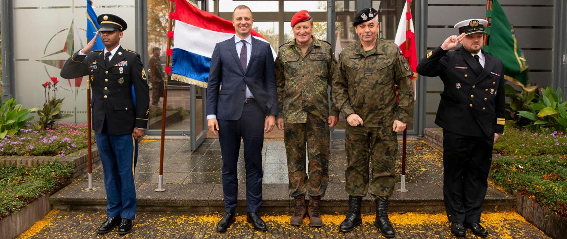 Ambasador Szatkowski stoi przed wejściem do jednostki w Brunssum w towarzystwie polskich i zagranicznych oficerów