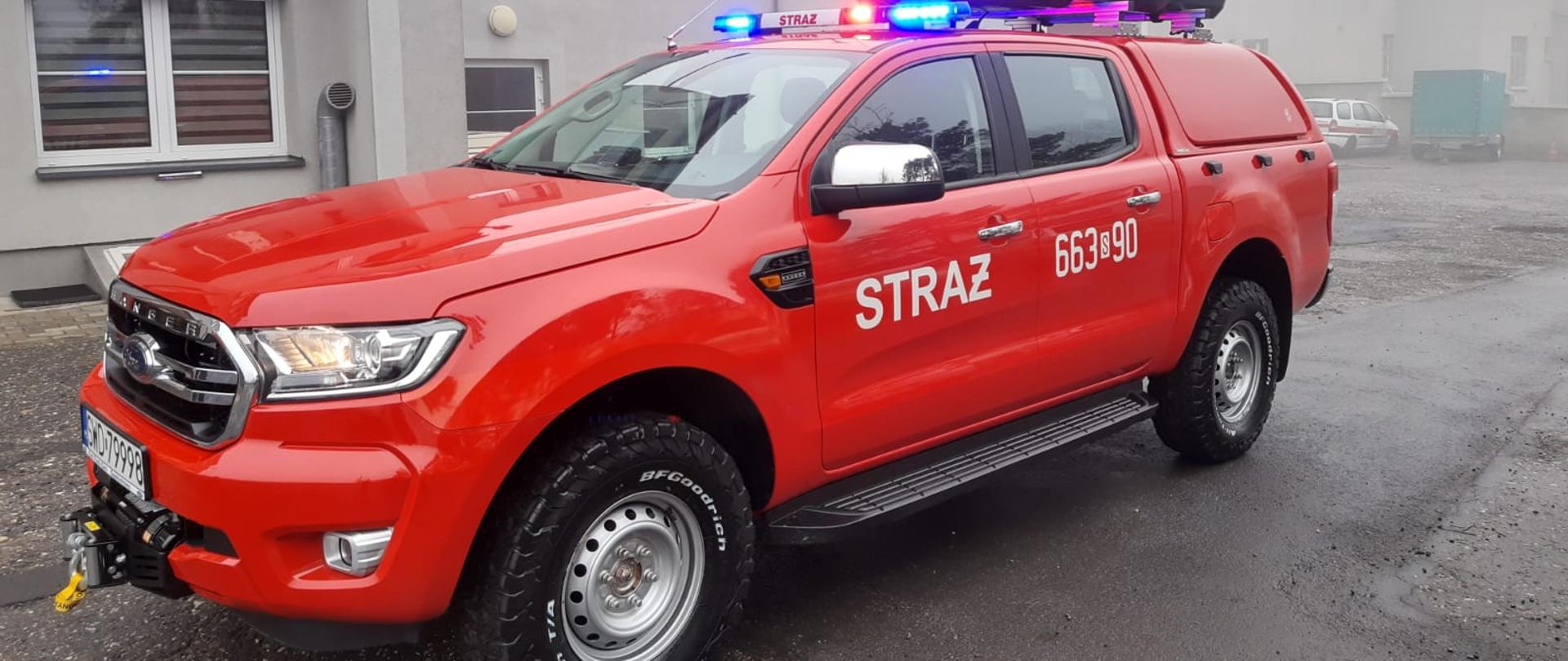 Zdjęcie przedstawia samochód rozpoznawczo-ratowniczy SLRR Ford Ranger na tle budynku Jednostki Ratowniczo-Gaśniczej w Rydułtowach