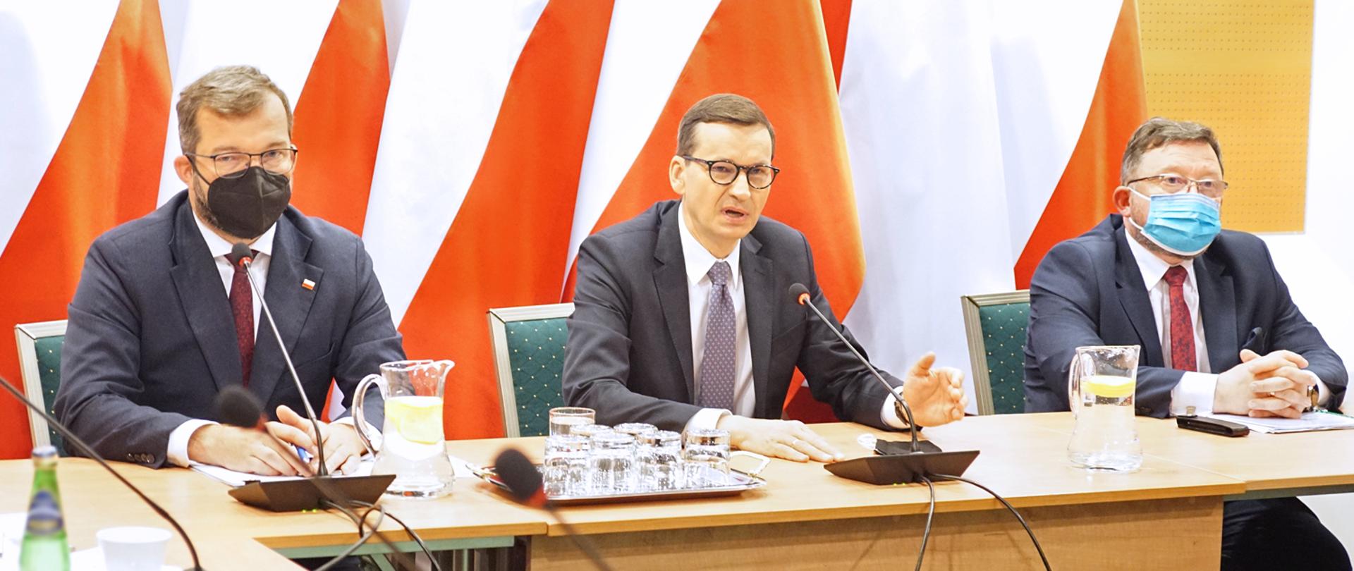 Premier Mateusz Morawiecki, minister Grzegorz Puda oraz główny lekarz weterynarii Mirosław Welz siedzący za stołem prezydialnym