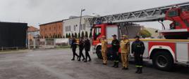 Poczet sztandarowy maszeruje by poidnieść flagę państwową. W tle samochód drabina pożarnicza.