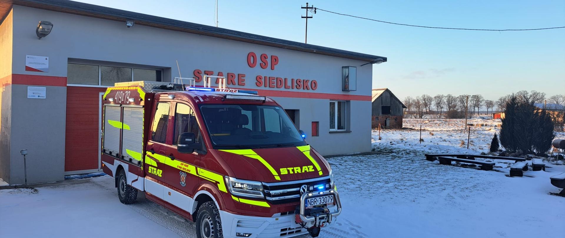 Przed remizą OSP Stare Siedlisko stoi nowy samochód strażacki. Zima dużo śniegu, pogodnie.