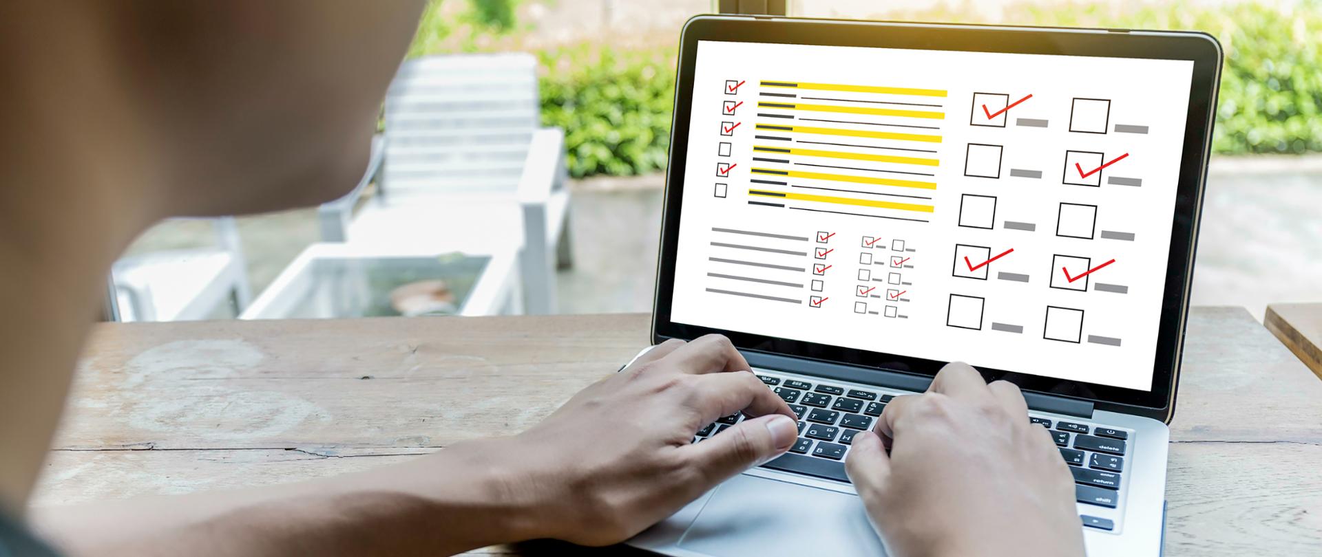 Mężczyzna wypełniający ankietę na laptopie w ogrodzie