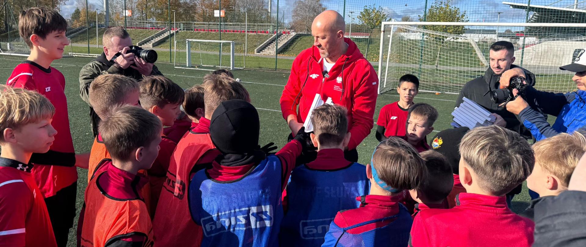 boisko do gry w piłę nożną, a na nim grupa dzieci w dresach