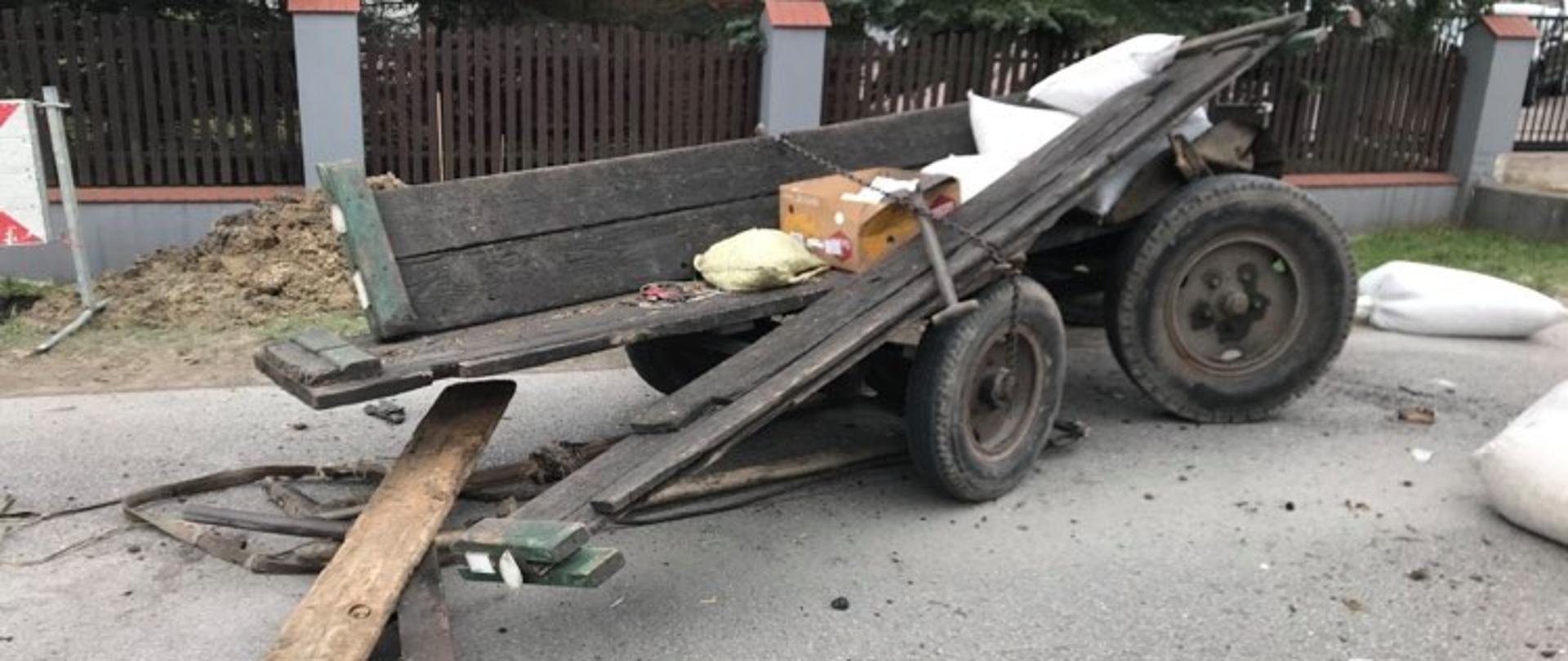 połamana furmanka stojąca na pasie jezdni