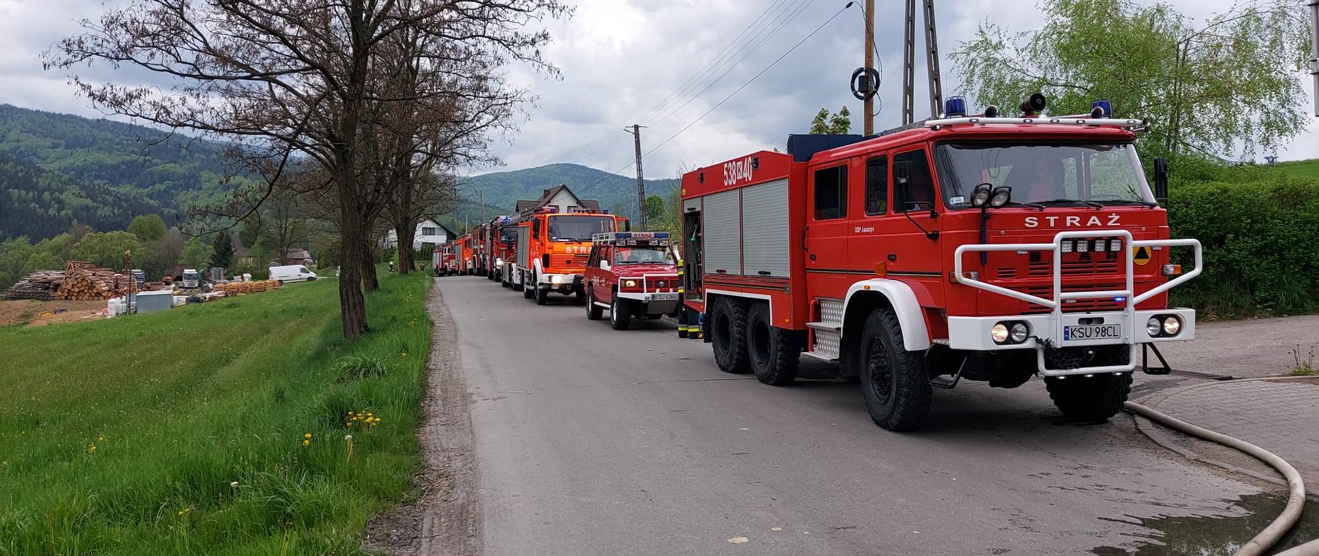 Zdjęcie przedstawia samochody strażackie, które przyjechały do pożaru