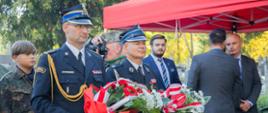 Komendant powiatowy PSP w Żyrardowie st. bryg. Mariusz Tymoszewicz wraz z byłym komendantem powiatowym PSP st. bryg. w st. spocz. Andrzejem Oklesińskim niosą wiązanki w celu ich złożenia pod pomnikiem.