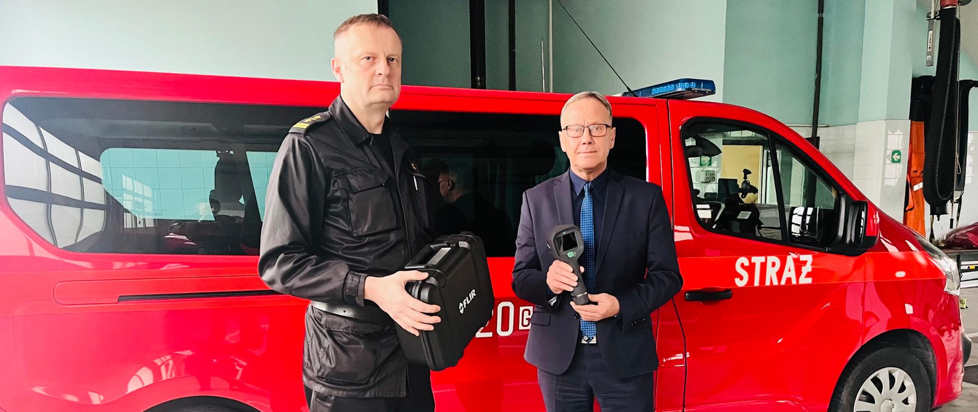 Zdjęcie przedstawia Komendanta PSP i Prezydenta miasta z przekazanymi urządzeniami. W tle samochód pożarniczy.