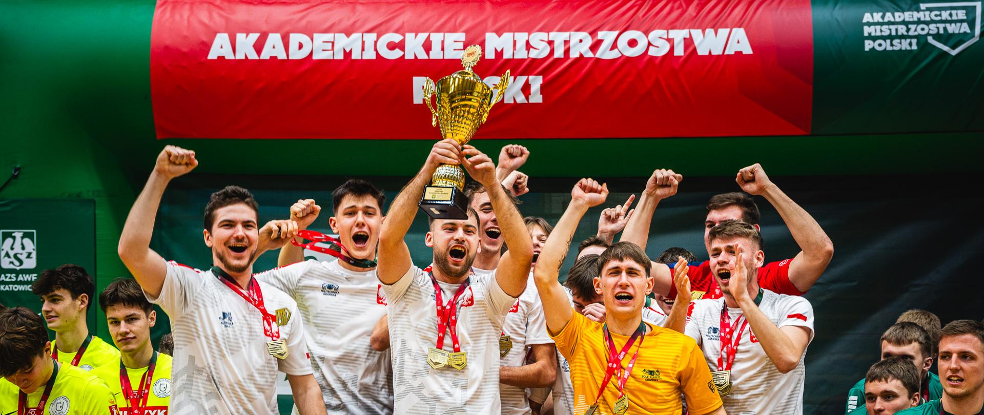 Zwycięzcy Akademickich Mistrzostw Polski w futsalu na tle zielonego balonu z logiem AZS